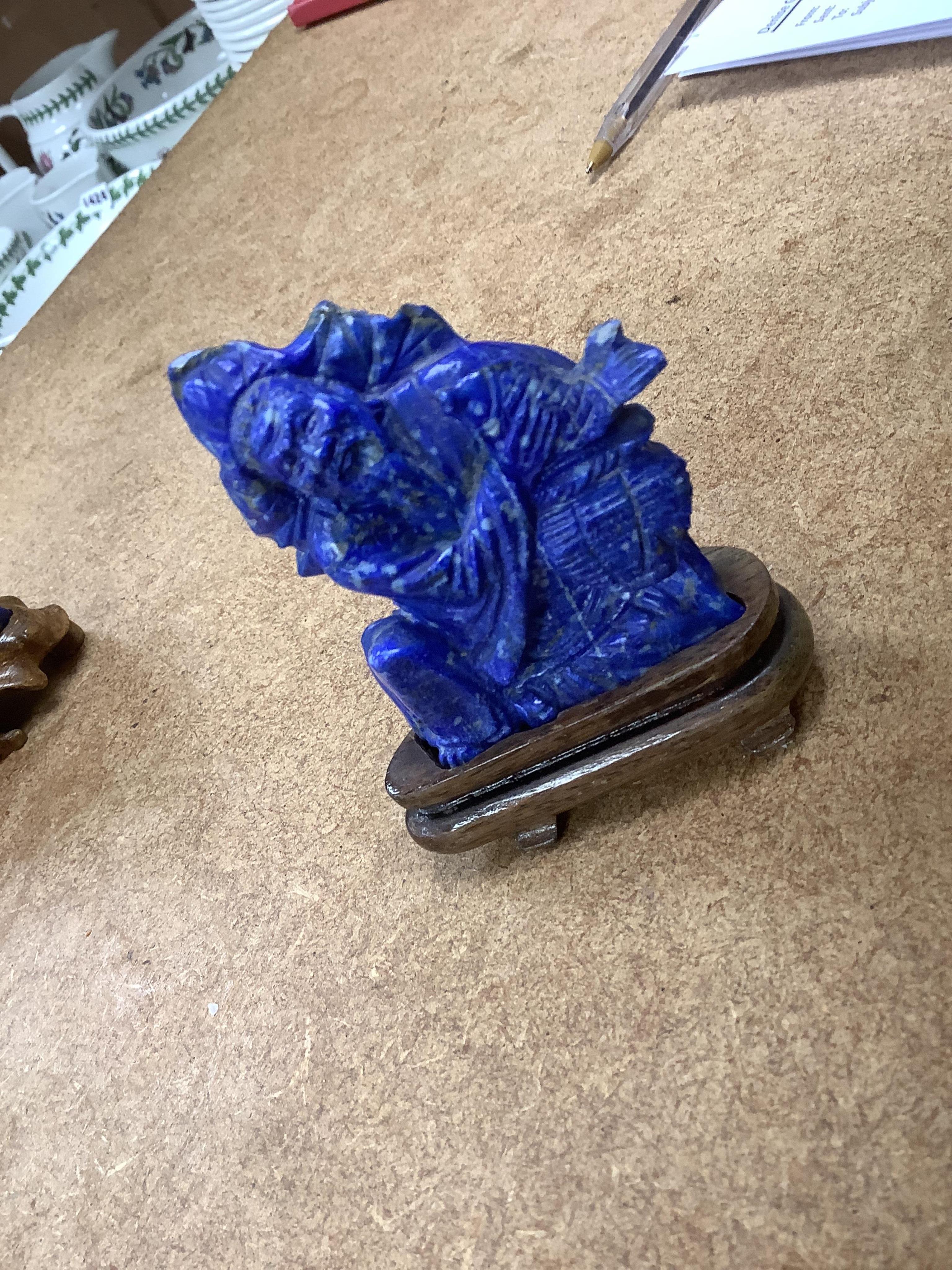 Six Chinese lapis lazuli carvings of immortals, wood stands and a Chinese coral carving of a woman reclining, Buddha on stand 11cm wide (7). Condition - fair